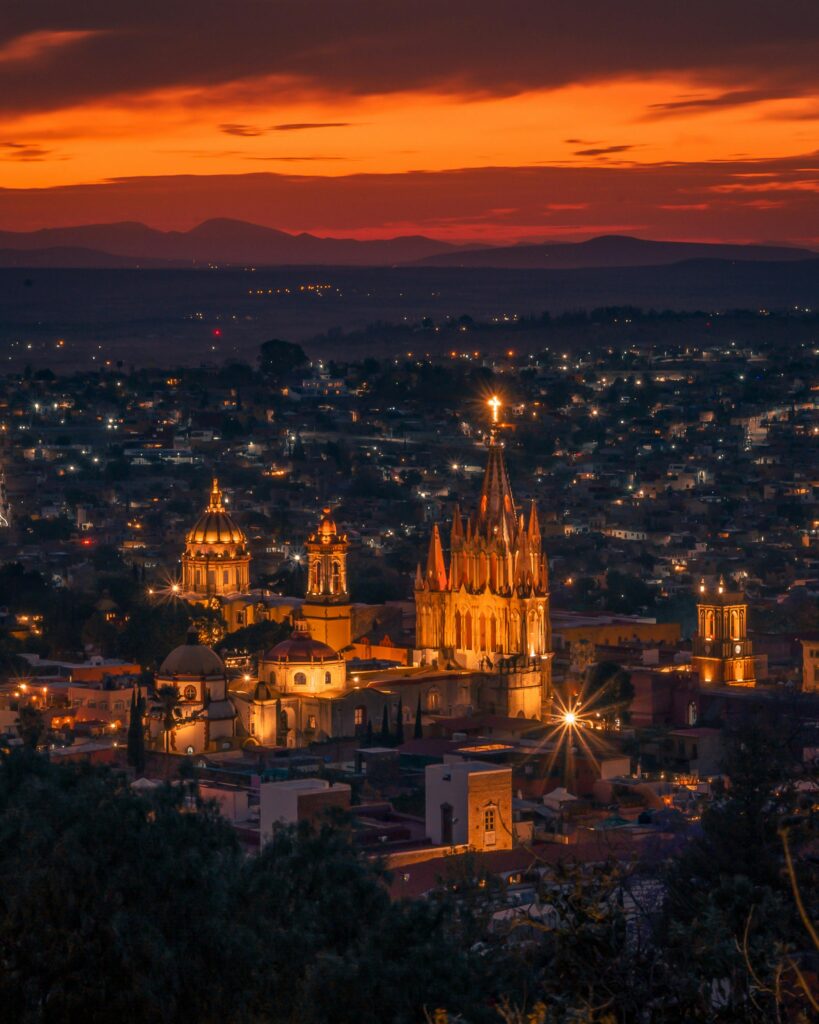 Stunning dusk view of San Miguel de Allende with illuminated cathedral and dramatic skyline.